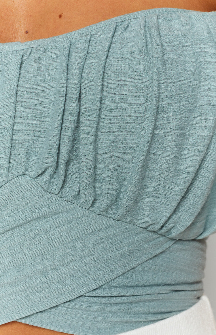 Sage off-the-shoulder wrap top with ruffled sleeves and textured fabric, tied at the side