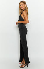 Side view of a black halter neck formal dress with a fitted bodice and high side split maxi skirt