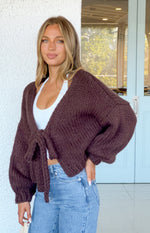 Front view of a chocolate brown chunky knit tie-up cardigan with voluminous balloon sleeves and ribbed cuffs