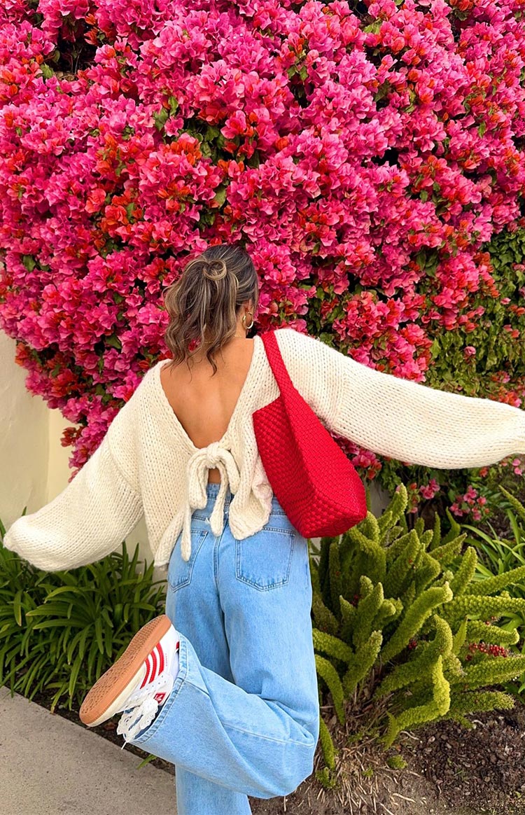 Side view of a cream chunky knit cardigan with a prominent side tie closure and relaxed long sleeves