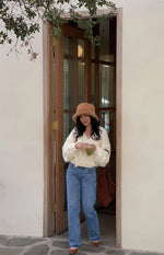 Full length view of a cream chunky knit wrap cardigan with a V-neck and tie waist, showing its cropped fit