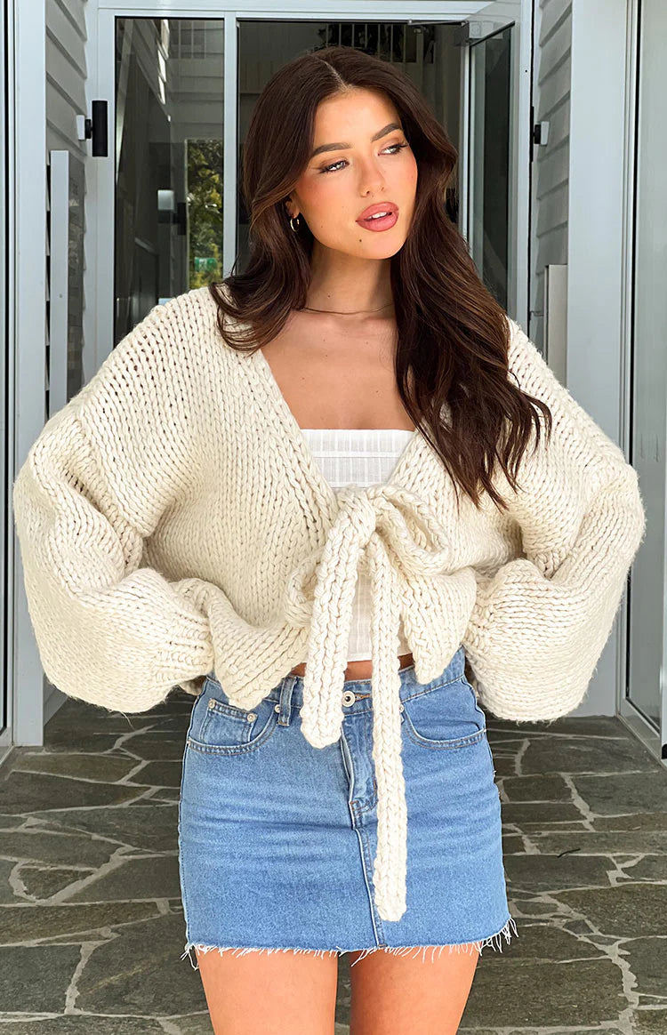 Cream chunky knit cardigan with a front tie closure, long sleeves, and a relaxed cropped fit