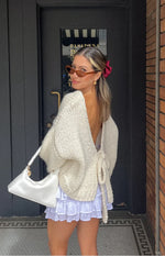 Detail shot of the cream chunky knit cardigan's front tie closure tied in a bow