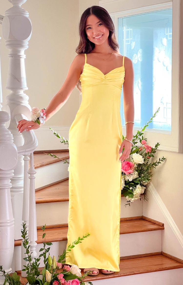 Front view of a honey yellow maxi dress with a ruched sweetheart neckline, thin spaghetti straps, and a fitted bodice