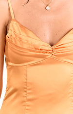 Close-up of the pleated and ruched bust detail on a honey orange satin mini dress