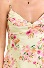 Close-up of the ruched bust detail and fitted bodice of a honey yellow satin mini dress with pink and orange floral print