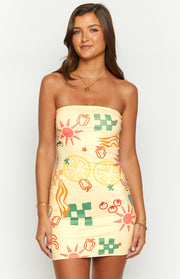Yellow strapless mini dress with a vibrant graphic print of suns, lemons, and checkerboard squares