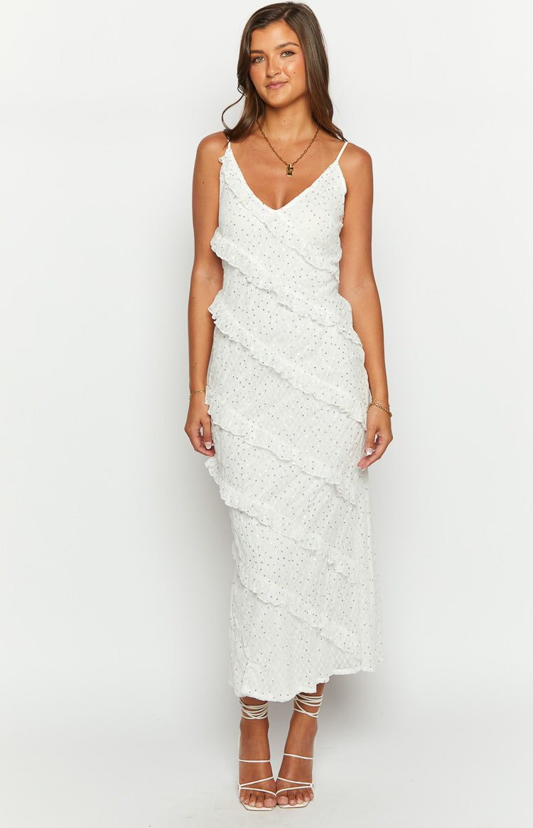 White V-neck maxi dress with spaghetti straps, subtle dotted texture, and layered diagonal ruffles
