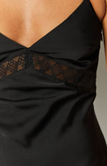 Rear close-up of the black maxi dress featuring a deep V-neckline and a patterned lace panel across the back