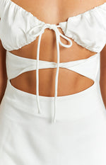 Close-up of the white mini dress showing the tie-front ruched bust and twisted fabric waist cutouts