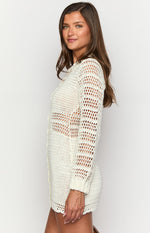 Side view of a cream crochet mini dress showing the open knit sleeves, side button placket, and varying crochet patterns