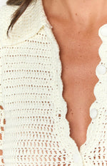 Close-up of the cream crochet mini dress showing the collared neckline, scalloped button placket, and white fabric-covered buttons