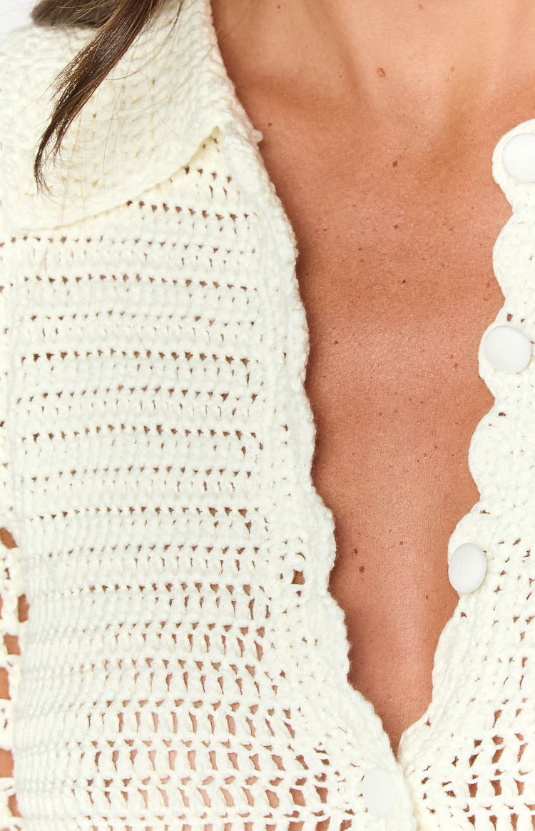 Close-up of the cream crochet mini dress showing the collared neckline, scalloped button placket, and white fabric-covered buttons