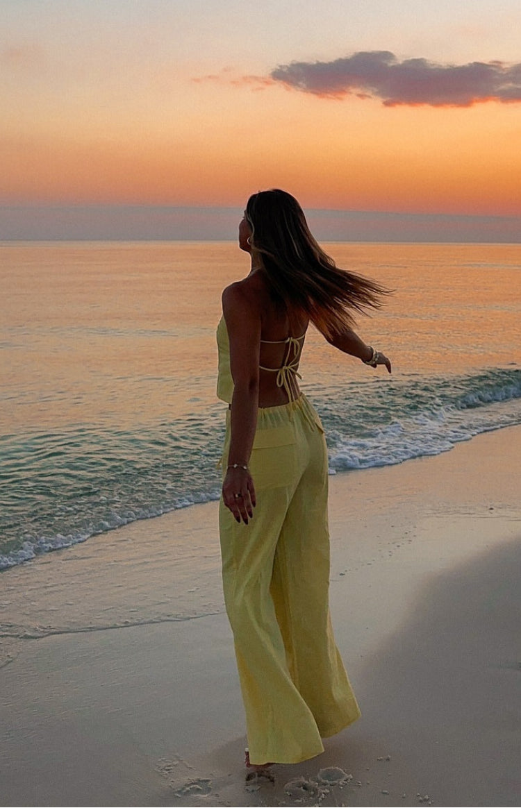 Rear view of a yellow crop top with thin criss-cross back straps and an open tie-back design