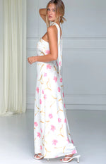 Side view of a cream satin maxi dress with pink floral print, showing the long self-tie detail and flowing skirt