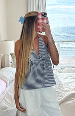 Front view of a blue and white striped halter neck top with a deep V-neck and tie-front waist detail