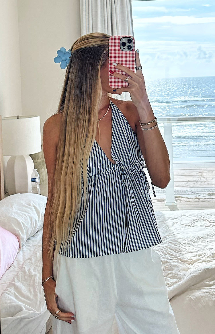 Front view of a blue and white striped halter neck top with a deep V-neck and tie-front waist detail