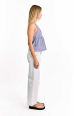 Side view of a blue and white striped top with thin spaghetti straps and a gathered side seam creating a loose flared fit