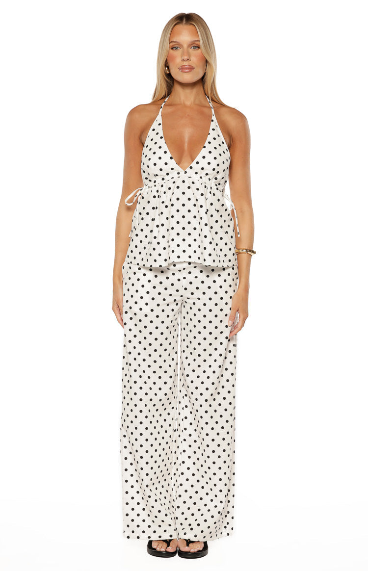 White polka dot halter neck top with deep V-neckline, sleeveless design, and adjustable side ties
