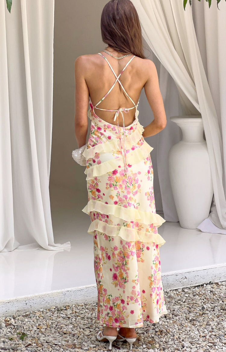 Rear view of a yellow bloom floral maxi dress with criss-cross back straps and tiered yellow ruffles