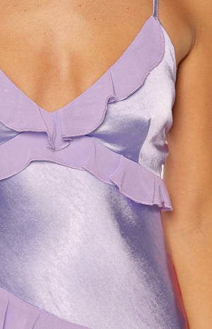 Close-up of the lilac satin fabric and sheer chiffon ruffles on the V-neckline of the maxi dress
