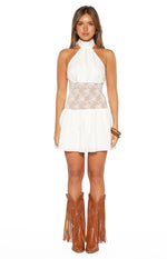 White halter neck mini dress with a sheer floral lace panel at the waist and a flowy skirt