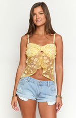Front view of a yellow sequin cropped top with a central bow detail, keyhole cutout, and floral appliques
