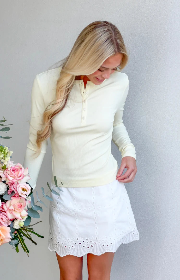 Yellow ribbed long sleeve top with a henley button placket and fitted silhouette
