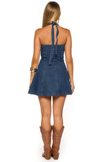 Rear view of the mid wash denim mini dress with halter ties at the neck and a fitted bodice leading to a flared mini skirt