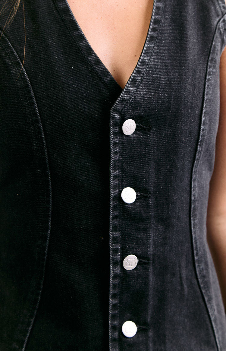 Close-up of the silver BB-logo buttons on the front placket of a black washed denim mini dress, showing V-neck