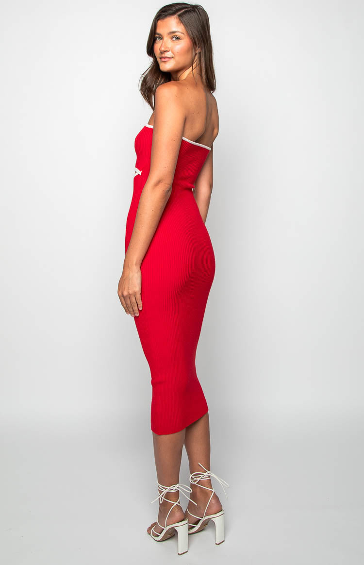 Side view of a red ribbed knit midi dress with white trim on the strapless neckline and a white X detail