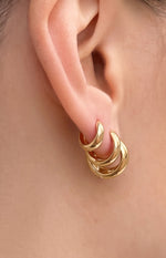 Three graduated gold huggie earrings stacked together, showing their snug fit