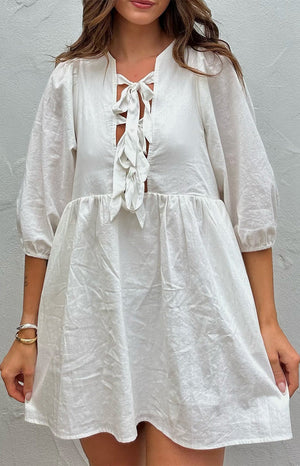 Beginning Boutique Issy White Mini Dress white textured mini dress with a lace-up V-neckline, 3/4 puff sleeves, and gathered babydoll skirt