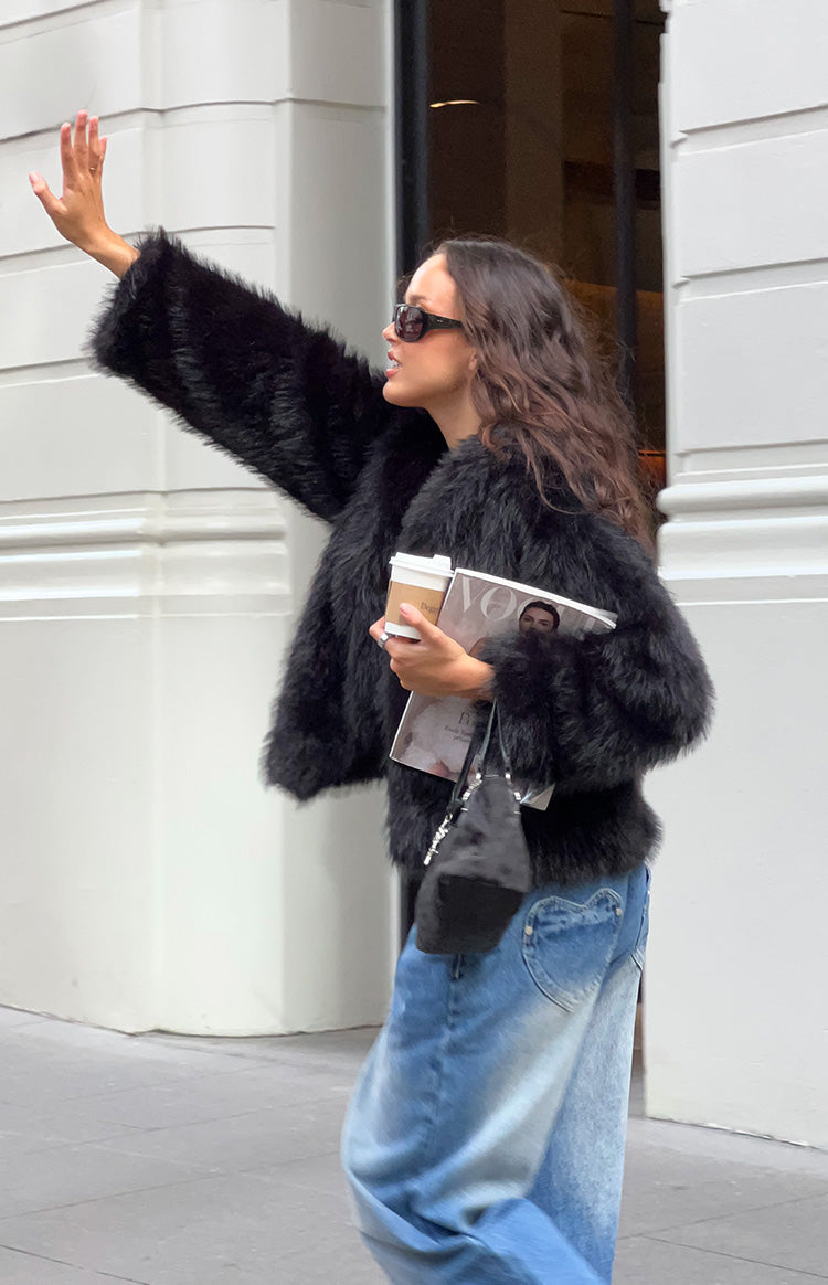 Side view of a black shaggy faux fur jacket with full sleeves and a cropped fit