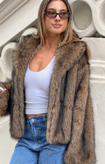Close-up of the chocolate faux fur jacket showing the textured fur and wide notched lapels