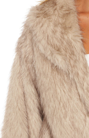 Woman wearing a luxurious sand faux fur jacket with wide leg jeans a glamorous choice for an Autumn event