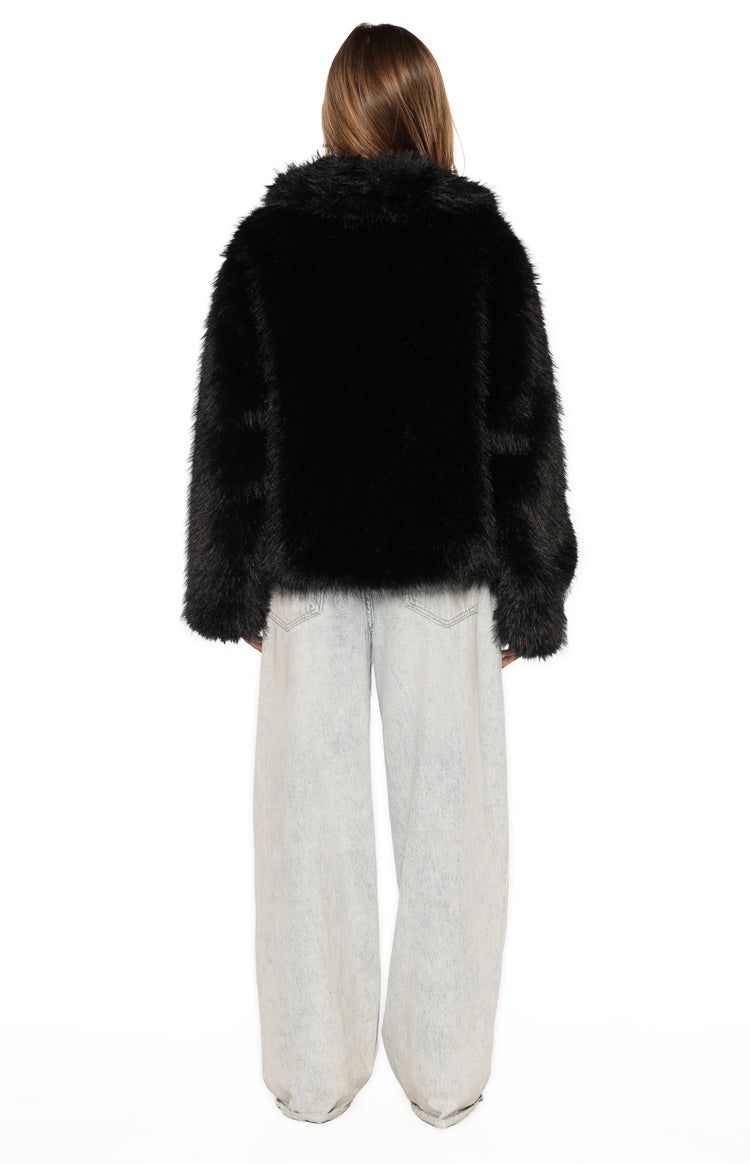 Rear view of a black faux fur jacket with a wide collar and relaxed long sleeves