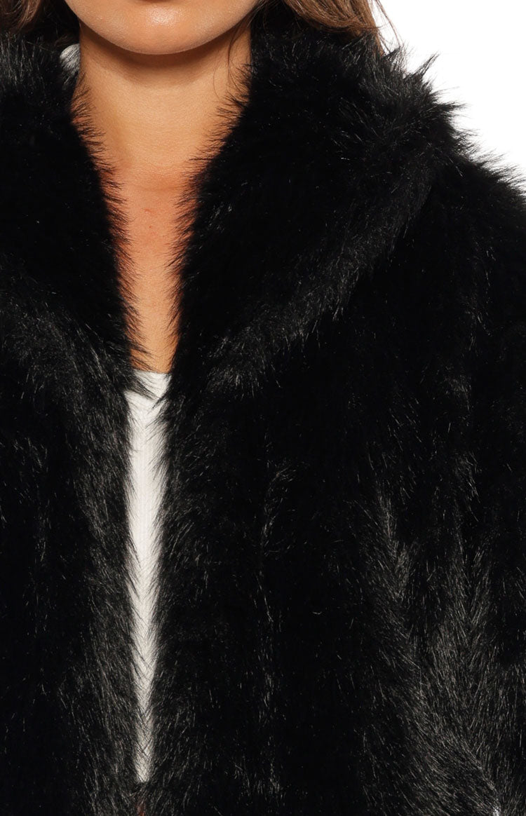 Detail shot showing the shaggy black faux fur texture and collar of the jacket