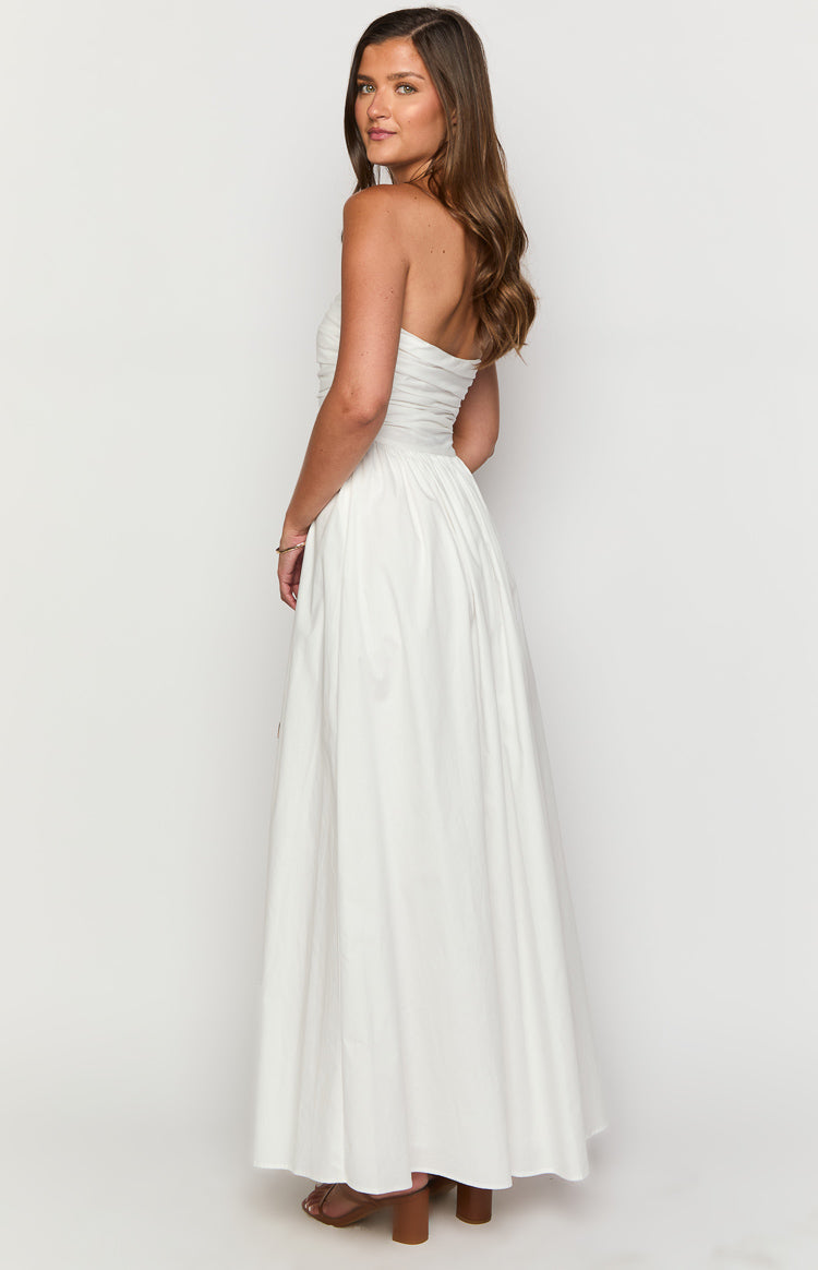 Side view of a white strapless maxi dress with a ruched bodice and a full, flowing skirt