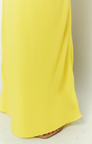 A close-up view of our skirt showing a pale yellow maxi skirt with a flowing silhouette that pools at the bottom. This skirt is made of a satin-like or chiffon-like material.