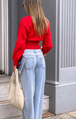 Rear view of a red knit oversized cardigan with a ribbed, cinched hem and long sleeves