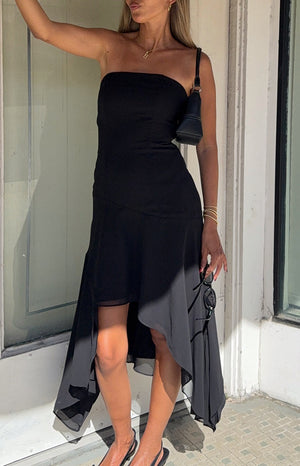 Black strapless midi dress with a fitted bodice and a flowy hanky hem skirt with a sheer overlay