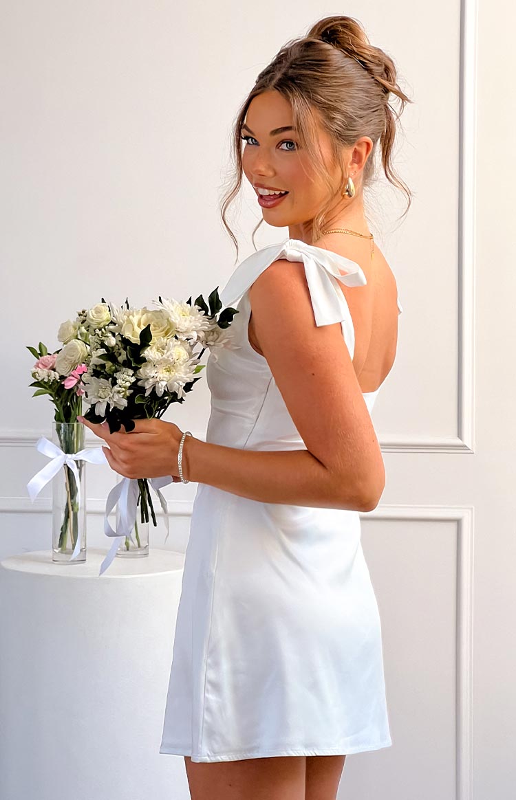 Side view of a white satin mini dress with tie-shoulder straps and a low scoop back