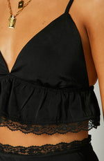 Close-up of the black crop top showing the ruffled hem with delicate lace trim and thin spaghetti straps