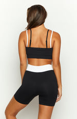 Rear view of a black ribbed ballet crop top with thin adjustable spaghetti straps