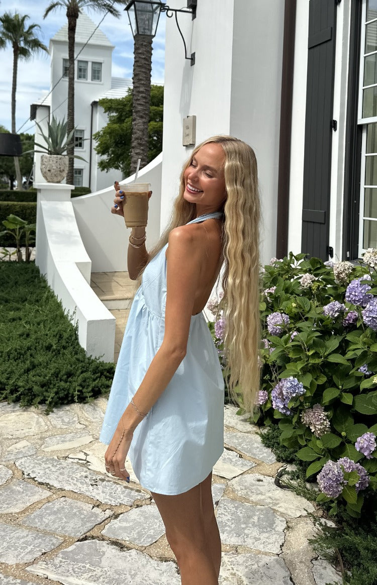 Side view of a light blue halter neck mini dress with an open back and flowy skirt