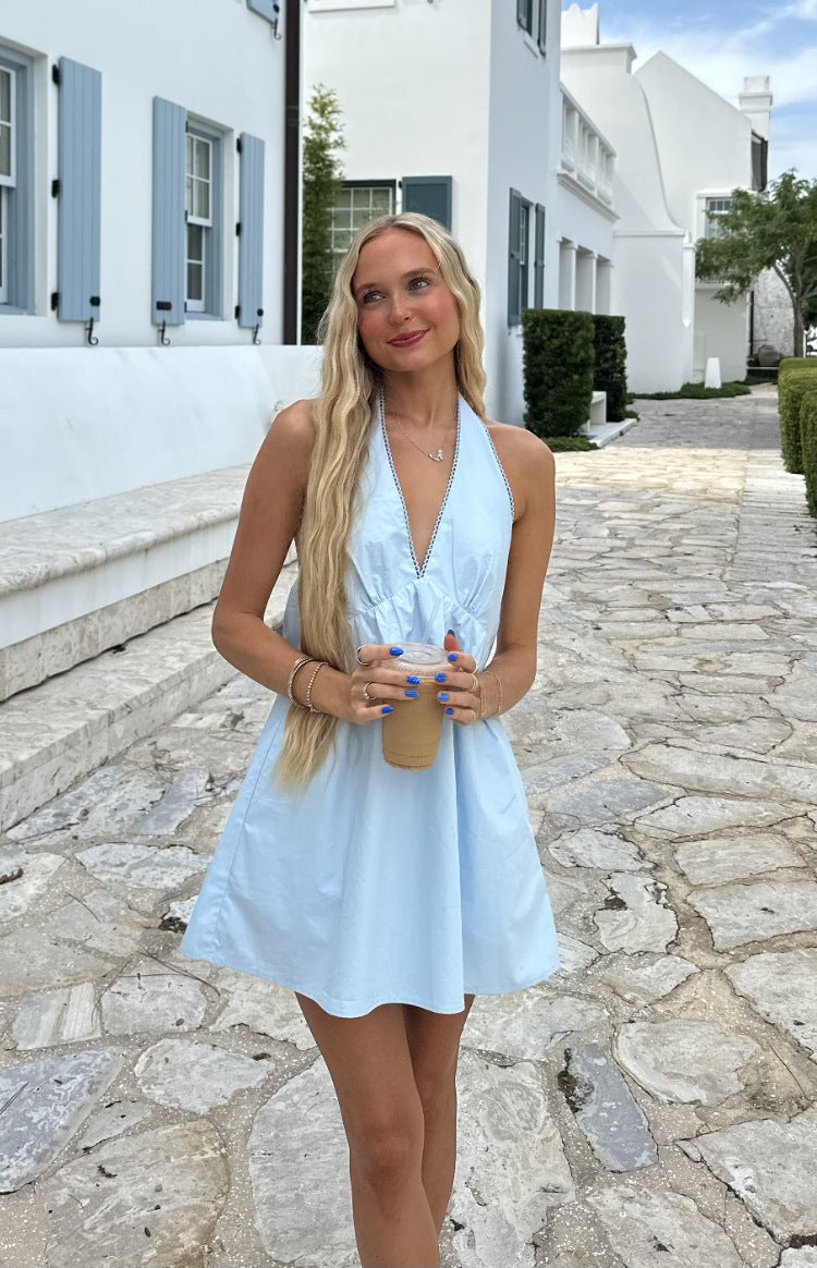 Front view of a light blue halter neck mini dress with a gathered bust and white scalloped V-neck trim