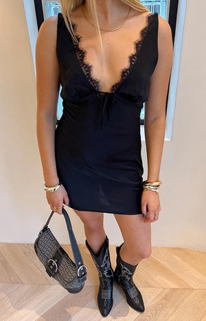 Brunette model stood infront of a white wall is wearing a black