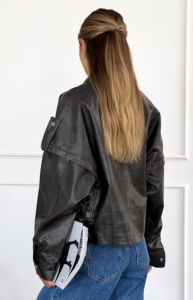 Rear view of a washed black PU jacket with an oversized fit, shoulder flap, and side lace-up detail