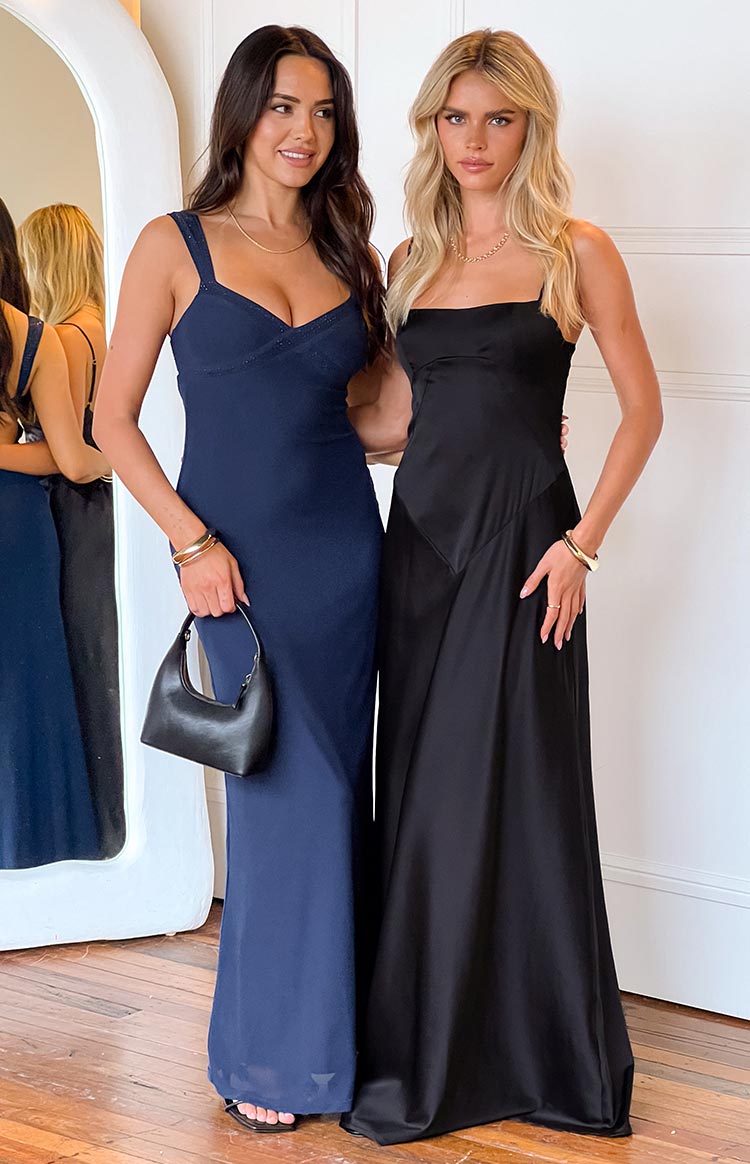 Black maxi dress with a square neckline, thin spaghetti straps, and a flowing skirt with subtle paneling